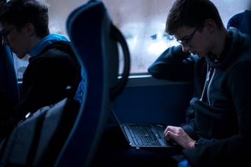 Nicolas working on his laptop during a bus drive