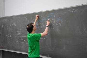 Photo of Johannes presenting a solution on the blackboard, colourful