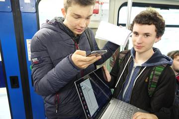 The winning team optimizing their time by solving problems on their computer while standing on the metro.